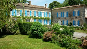 A traditional stone building with blue shutters and a well-maintained garden. - Le Logis de Faugerit (Frontenay-Rohan-Rohan)