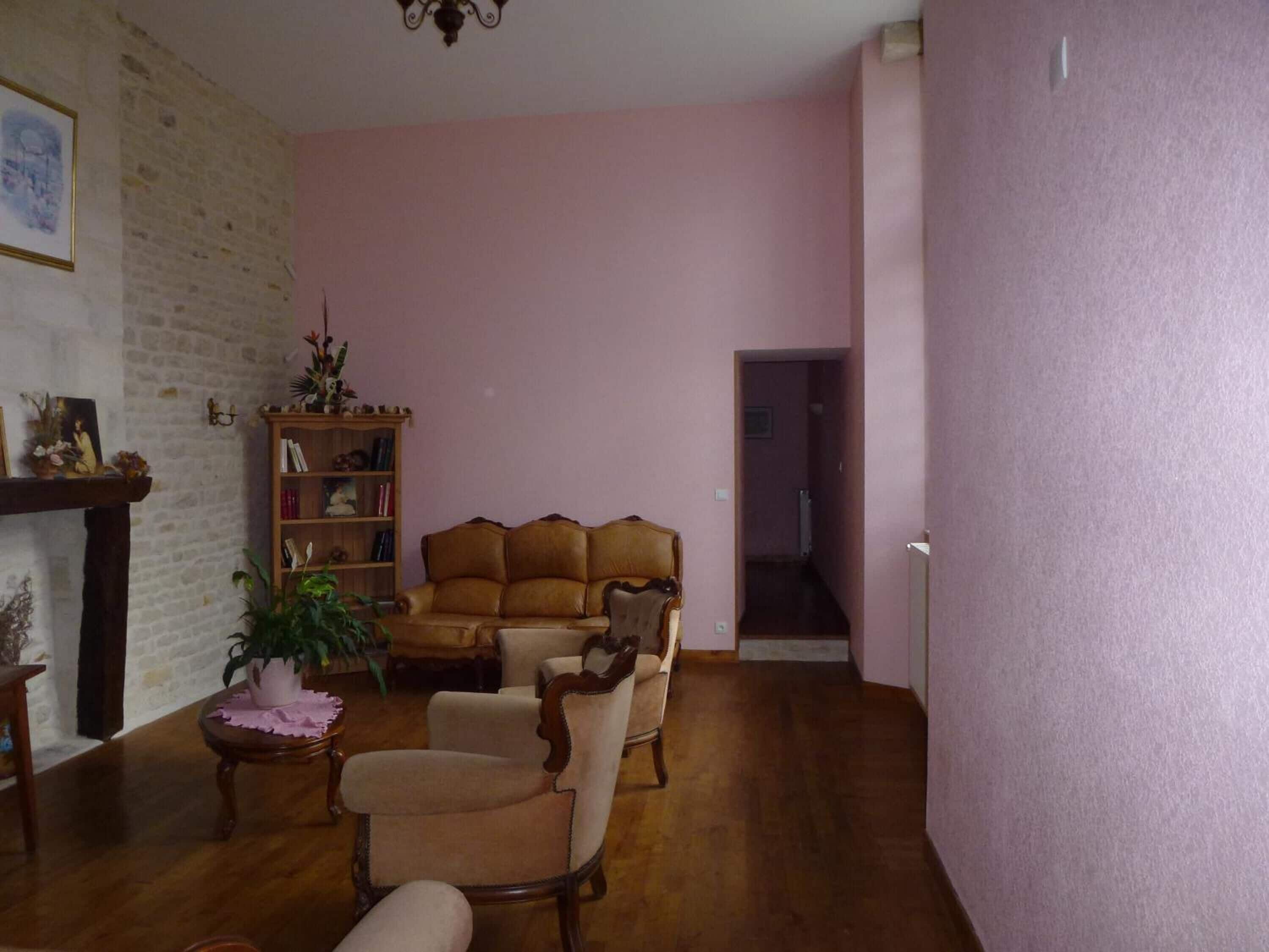 Un salon avec un canapé en cuir marron, une chaise en bois, une bibliothèque et une cheminée.