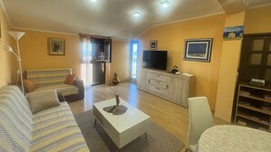 Uma sala de estar com sofá, mesa de centro, televisão e armário.