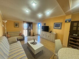A living room with a sofa, a coffee table, a TV, and a cabinet.