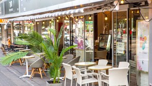Un café al aire libre con mobiliario de mimbre y plantas en macetas.