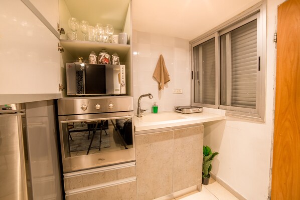 A compact kitchen with a built-in oven, microwave, and sink.