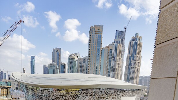 Un balcone con vista su un panorama urbano, che include grattacieli e gru da costruzione.