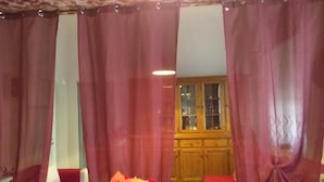 A room with a bed, a wooden cabinet, and red curtains. - Onda su Onda (La Spezia)