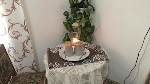 A small round table with a white tablecloth and a decorative plate, accompanied by two chairs with floral upholstery. - Onda su Onda (La Spezia)