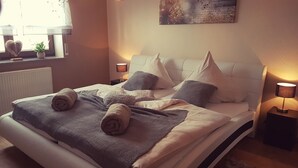 A neatly made bed with rolled towels, a bedside lamp, and a window with a view of the outdoors. - Eifel Dream Zingsheld (Fleringen)