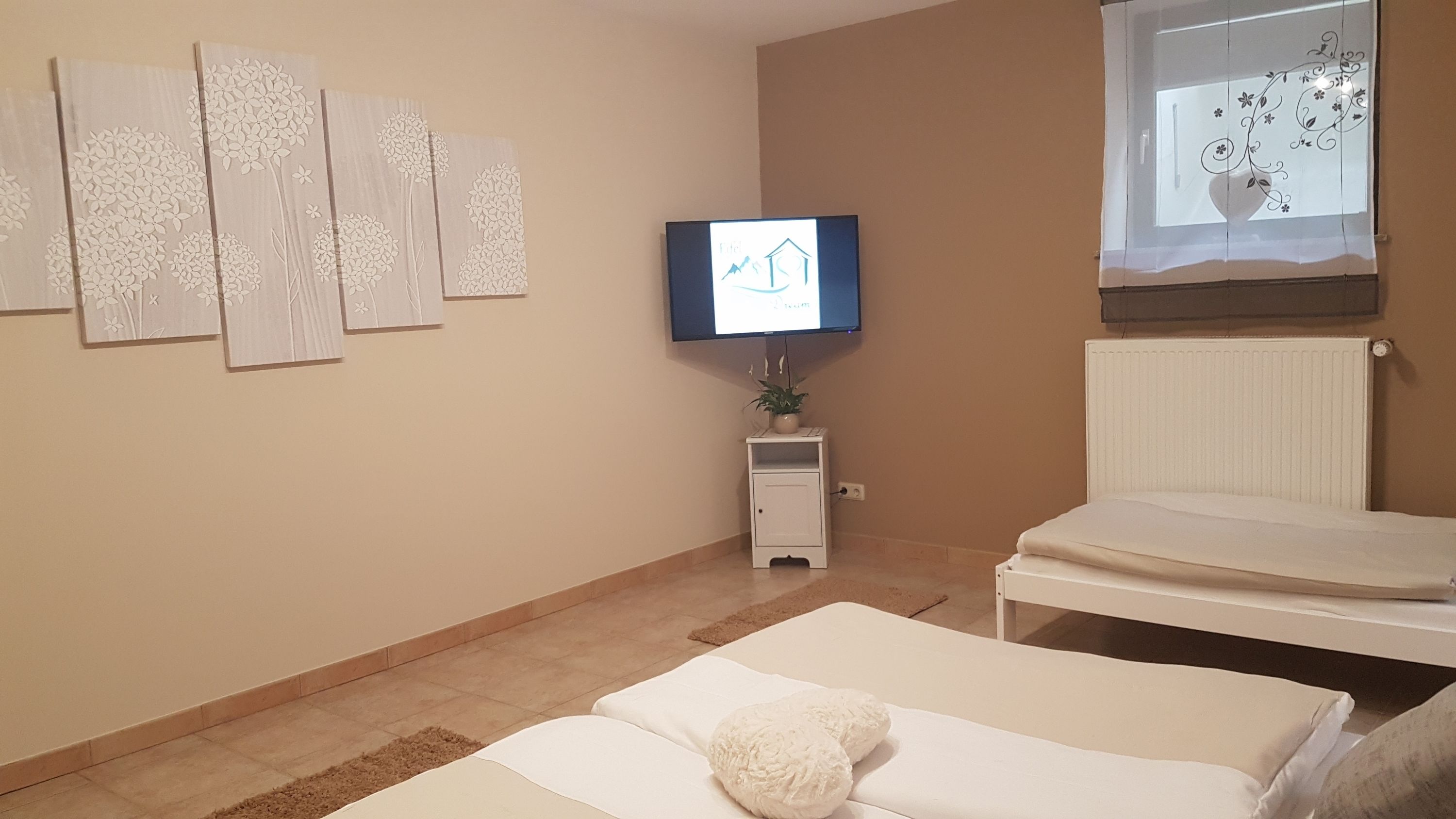A hotel room with a bed, a TV mounted on the wall, and decorative wall art.