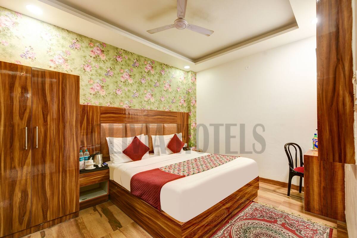 Quarto de hotel com cama de madeira, mesa de cabeceira, cadeira e papel de parede floral.