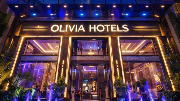 The exterior of Olivia Hotels with a modern glass facade, illuminated entrance, and a visible pool area. - Olivia Hotels @ Delhi Airport (New Delhi)