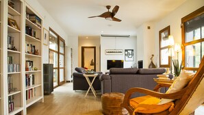 Un salón amplio con sofá, sillón de madera y estantería llena de libros.