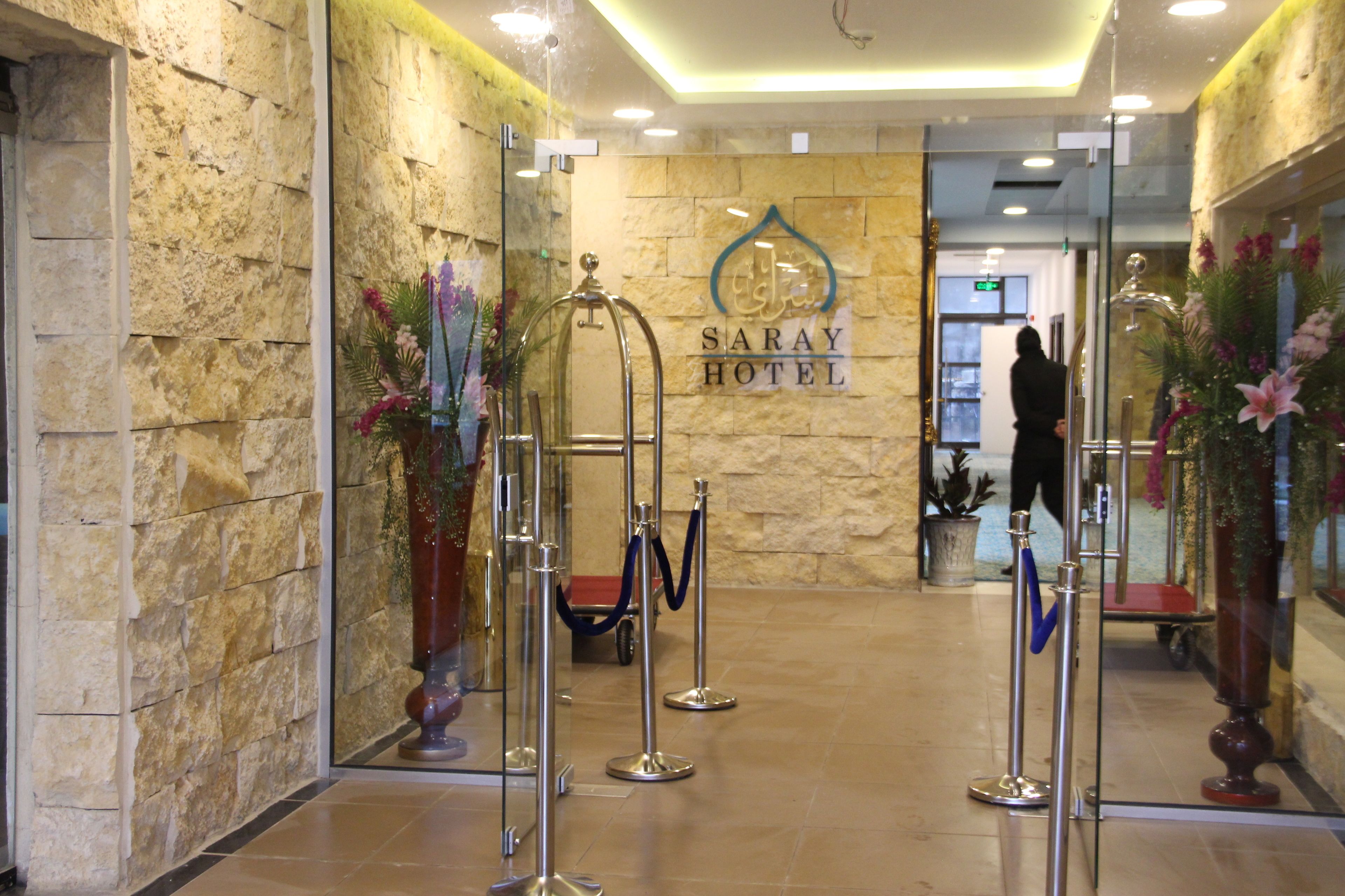 L’entrée de l’hôtel Saray, avec un mur en pierre, un comptoir d’accueil et une personne à l’arrière-plan.