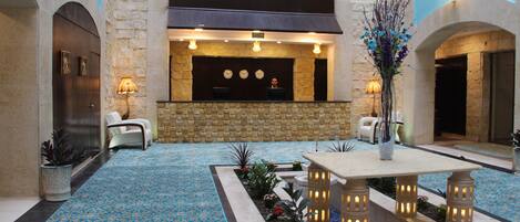 A lobby with a reception desk, seating area, and decorative plants.