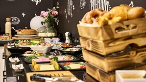 A buffet setup with various food items and a decorative wall in the background. - Hotel Alter Wirth (Geretsried)