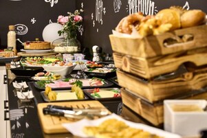 A buffet setup with various food items and a decorative wall in the background.