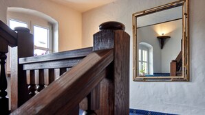 A wooden staircase with a balustrade, a large mirror on the wall, and a patterned carpet. - Hotel Alter Wirth (Geretsried)