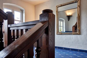 A wooden staircase with a balustrade, a large mirror on the wall, and a patterned carpet.