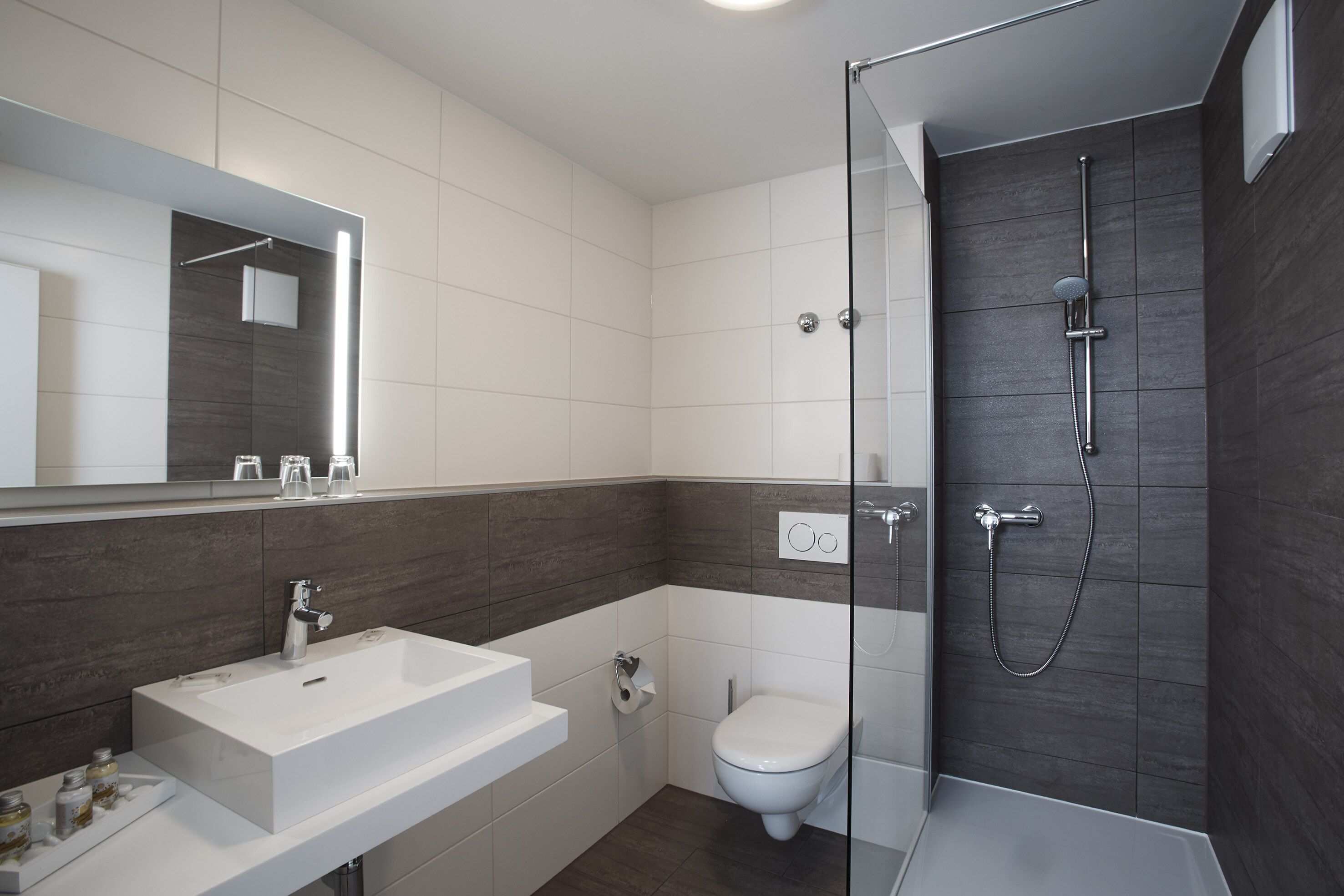 A modern bathroom with a white sink, toilet, and glass-enclosed shower.