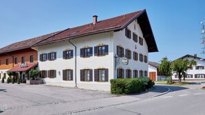 A two-story hotel with a red-tiled roof, multiple windows with shutters, and a sign indicating it is a hotel. - Hotel Alter Wirth (Geretsried)