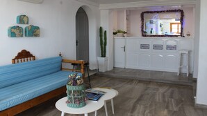 A living room with a blue sofa, a small table with a decorative birdcage, and a white cabinet with labels. - Stelios View Mykonos Town (Mykonos)