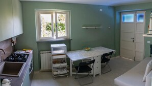 Una cocina compacta con estufa a gas, microondas y una pequeña mesa de comedor con sillas.