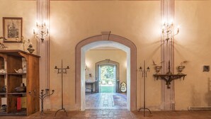 A hallway with a wooden floor, an arched doorway, and two wall-mounted chandeliers. - Bomarzo Ancient Villa (Bomarzo)