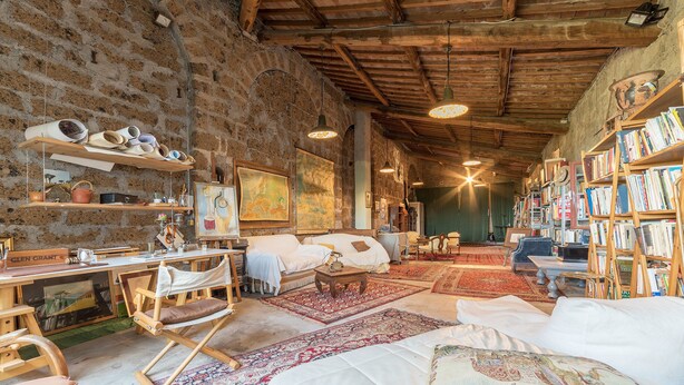 A cozy, rustic room with exposed brick walls, wooden beams, a large bed, a desk, and a bookshelf filled with books. - Bomarzo Ancient Villa (Bomarzo)