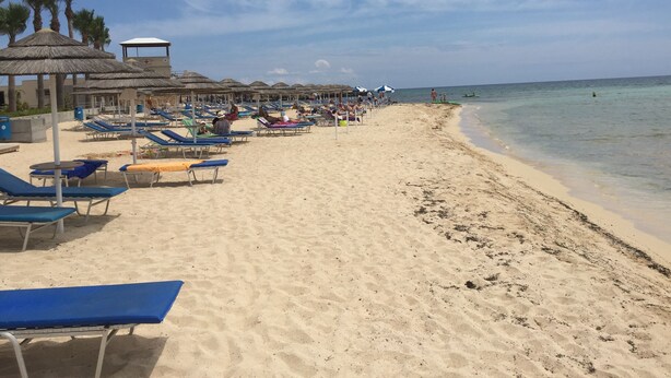 A beach with sun loungers and umbrellas, a lifeguard tower, and clear skies. - Penthouse Spacious  2 Bedroom Apartment with massive balcony in lovely Town (Xylofagou)