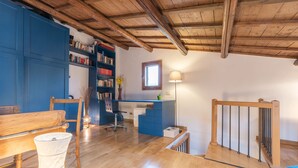 Una habitación amplia con techo de madera, una estantería azul, un escritorio y una ventana.