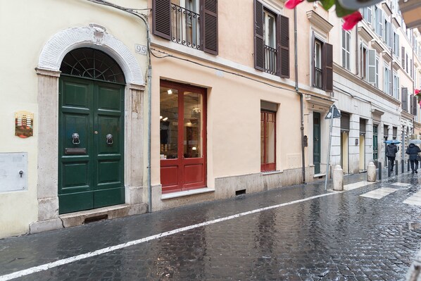 A narrow cobblestone street with historic buildings, a green door, and a red door. - Boschetto Peaceful Apartment (Rome)