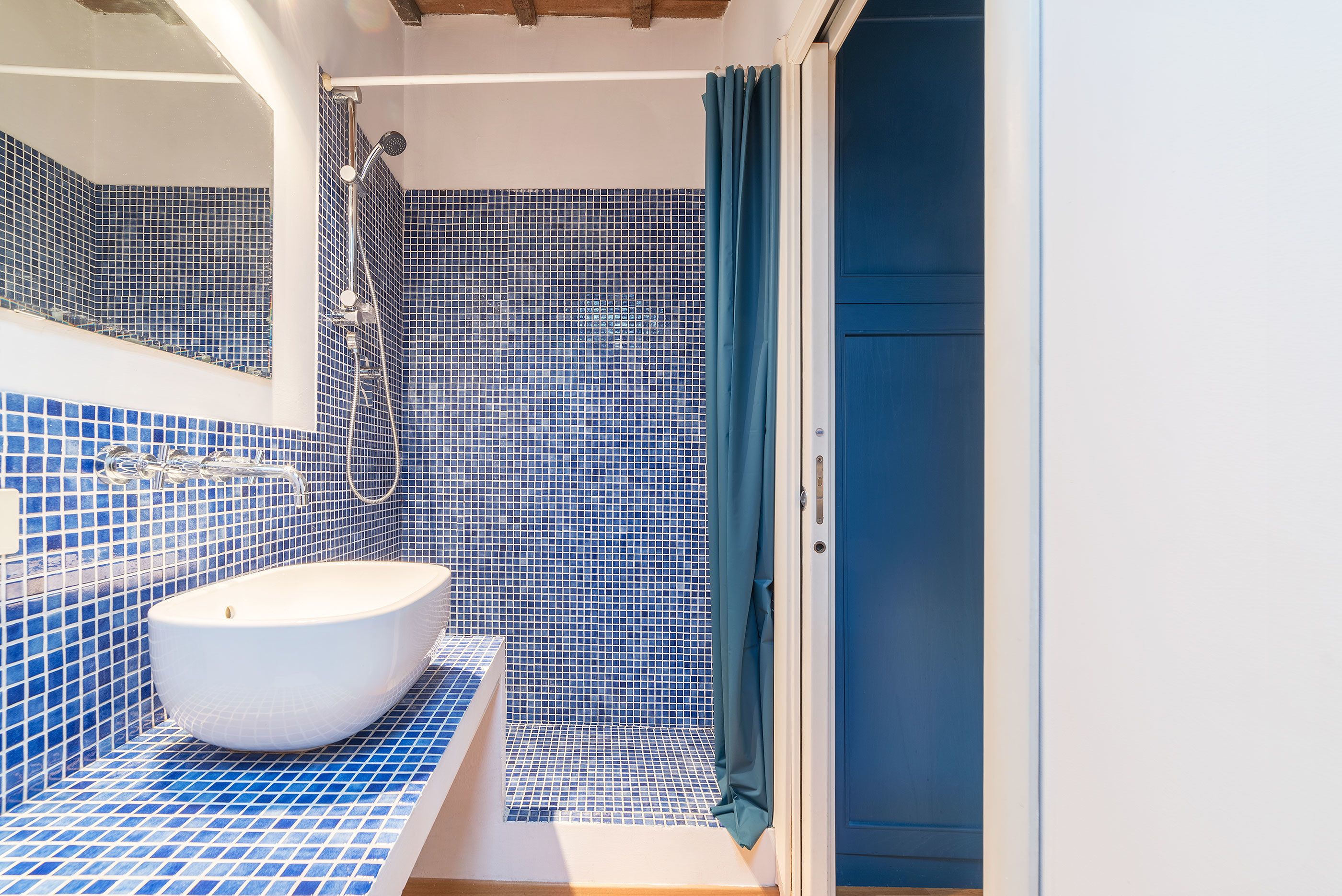 Ein Badezimmer mit einem weißen Waschbecken, blauen Fliesen und einer Duschkabine.
