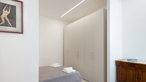 Une chambre à coucher avec un lit, une armoire et un petit meuble.