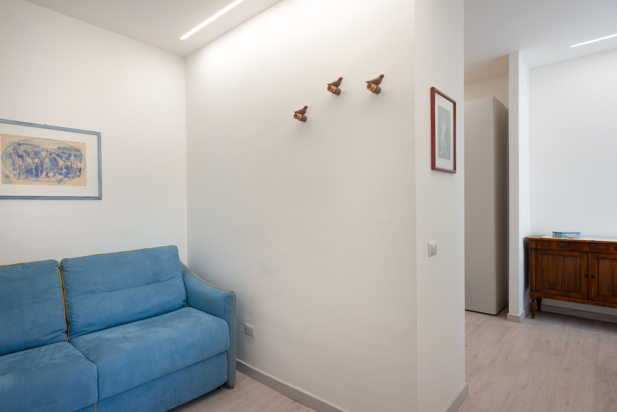 A room with a blue sofa, a wooden cabinet, and a framed picture on the wall.
