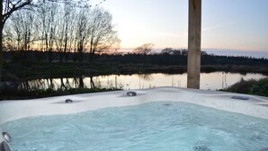 A hot tub with a view of a lake and trees at sunset. - Idylic country cottage with hot tub on private estate (Challock)