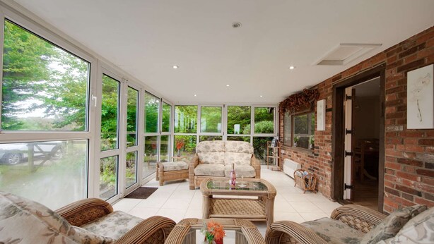 A spacious room with large windows, wicker furniture, and a brick wall. - Idylic country cottage with hot tub on private estate (Challock)