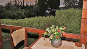 A wooden deck with a wicker chair and a vase of flowers on a tiled table. - Eden Ramot Chalets (Ramot)