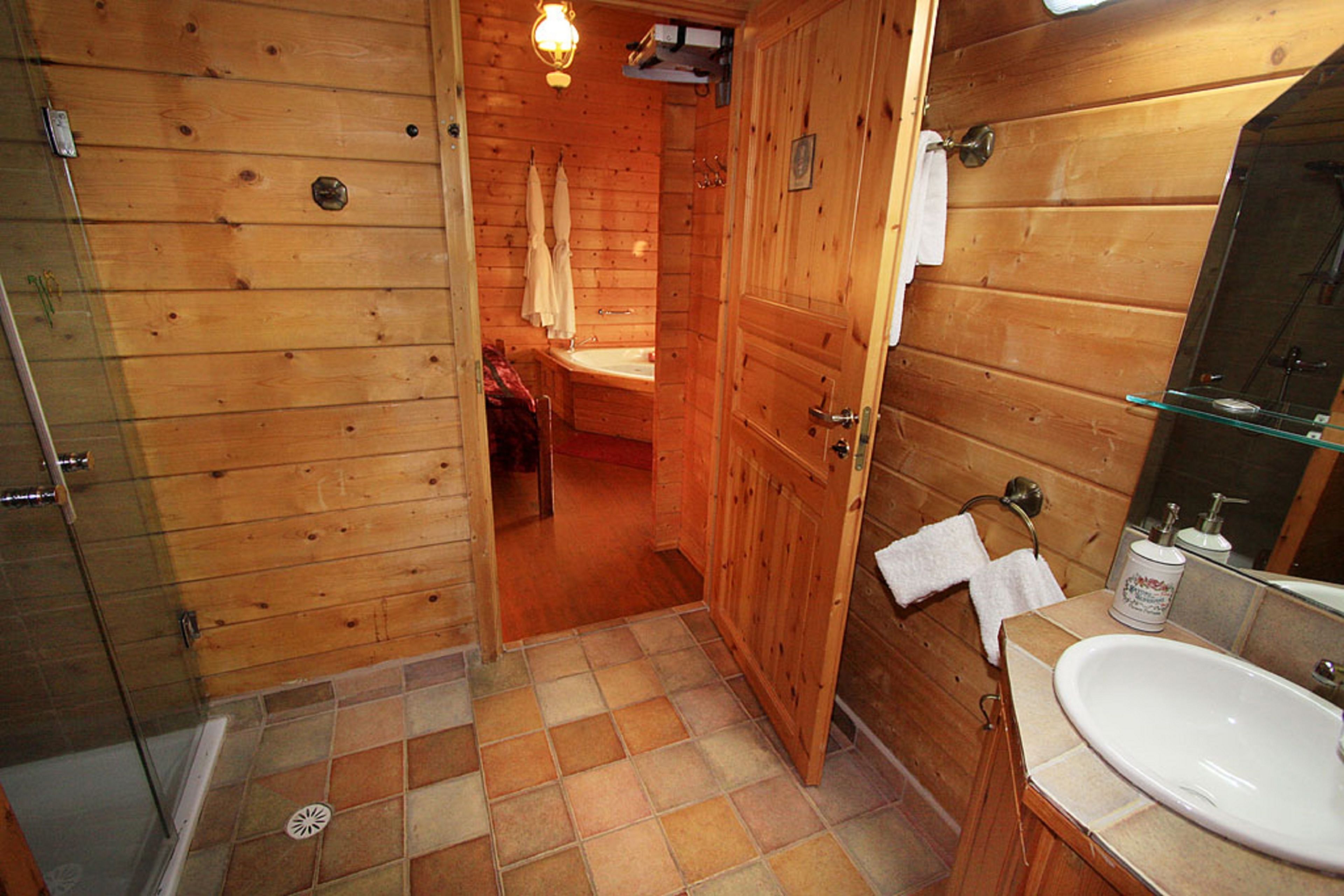 A wooden bathroom with a sink, mirror, and shower.