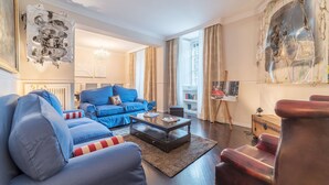 Un salon avec un canapé bleu, une table basse en bois et un fauteuil en cuir rouge.