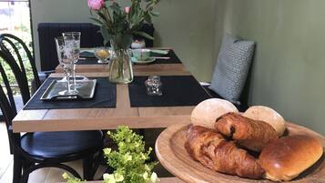 Ein Esstisch mit Holzbeschichtung, eine Vase mit Blumen, eine Brotschale und ein Glas Wasser.
