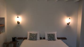 A bedroom with a large bed, two bedside tables, a nightstand, and wall-mounted lights.