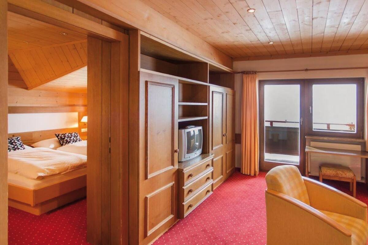 A cozy room with a bed, a TV, a desk, and a chair.