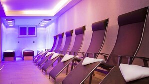 A row of reclining chairs in a room with a tiled floor and purple lighting. - Hotel & Art Kristiana (Saalbach-Hinterglemm)