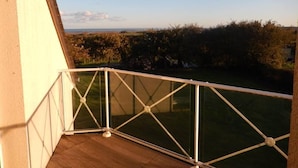 A balcony with a glass railing overlooking a grassy area and trees. - HOUSE WITH SEA VIEW ON NICE PLOT (Crasville)