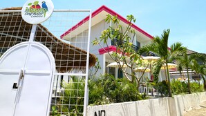 A hotel with a white gate, a sign reading "Mar Carita Star Hostet Canggu," and a building with a red roof and white walls. - Margarita Surf Hostel Canggu (Pererenan)