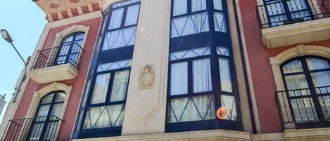 A building with large windows, balconies, and a prominent crest emblem.