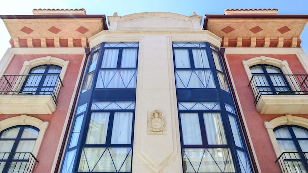 A building with a symmetrical facade, large windows, and a central decorative element. - Alda Vía de la Plata Rooms (La Baneza)