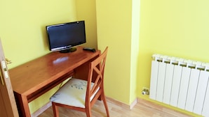A room with a wooden desk, a chair, a television, and a radiator. - Alda Vía de la Plata Rooms (La Baneza)