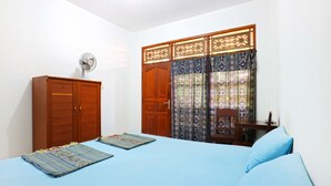 A bedroom with a bed, a wardrobe, a desk, and a chair. - Inada Losmen (Seminyak)