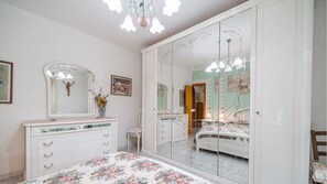 Ein Schlafzimmer mit großem Spiegel, Kommode, Bett und einer Chandelier.