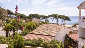 A residential area with terracotta-tiled roofs, lush greenery, and a view of the sea.