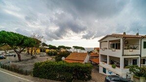A coastal residential area with a two-story building featuring balconies and a view of the sea.